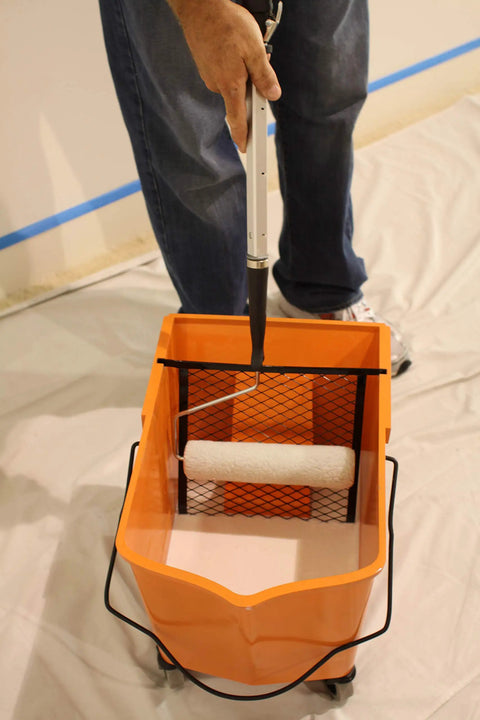 Person using RBC-323 Roll A Bucket With 3 Inch Caster Wheels And Brake 6 Gallon Orange Rolling Bucket For Paint And Tarps