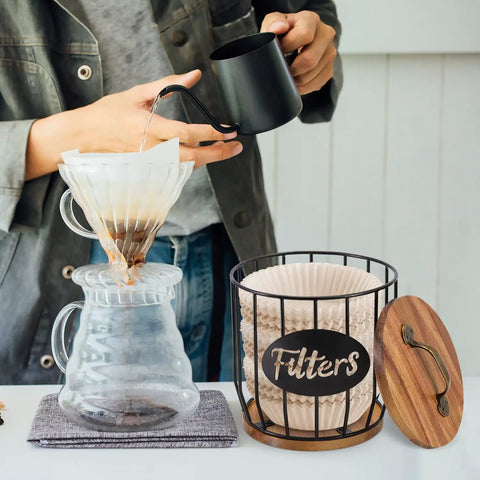Person brewing coffee with a Rustic Coffee Filter Holder With Lid Built From Acacia Wood And Metal Convenient Countertop Dispenser