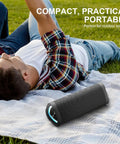 Rugged Portable Bluetooth Speaker With 24W Stereo Sound IPX7 Waterproof placed on a picnic blanket with RGB lights on.