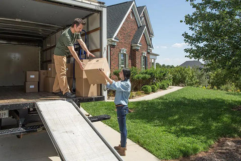 Two people unloading boxes from a moving truck outside a house, Ultra Tough Packing Tape With Dispenser For Moving And Shipping, Clear 2.83 Inch By 35 Yard, 3.4 Mil Thick, Holds Like A Boss And Easy To Cut, Ideal For Boxes And Storage, Pack Of 1.