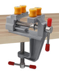 Rock Steady Mini Bench Vise Snags Loose Pieces For Jewelry Woodcarving And Watch Repair Ace Portable Table Vice with yellow grips on a wood surface.