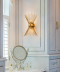 Gold Starburst Wall Sconce Vanity Light With Two Bulbs For Bathroom Hallway And Bedroom Mid Century Modern Indoor Lighting Vintage Style Wall Lamp Dope Vibe Home Decor 11 By 4.7 By 15.8 Inches mounted on wall in elegant bathroom setting.