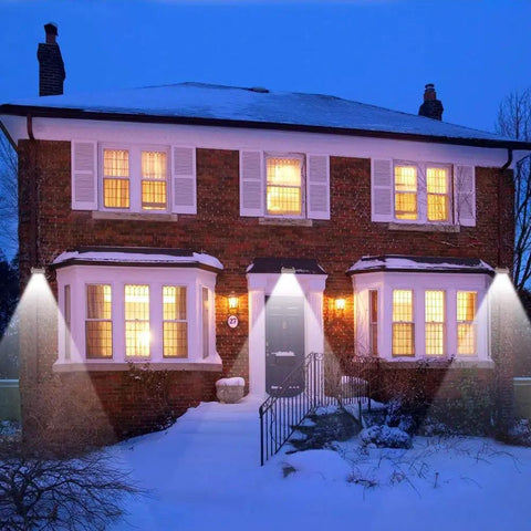 Lit Outdoor Solar Motion Sensor Wall Lights With 24 LEDs, illuminating snowy yard and brick house, pack of 4 shown