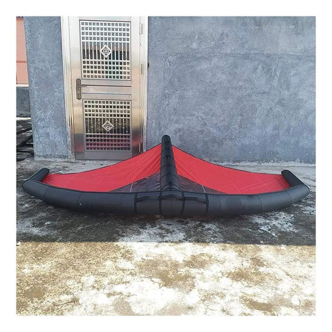 Red and black Handheld Inflatable Surf Wing For Windsurfing And Kiteboarding Do It All Water Sports Wing in outdoor setting.