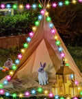 Lit 32 8Ft RGB Fairy Lights With 66 Acrylic Star LEDs illuminate a tent setup with bunny, lanterns, and festive decor outdoors.