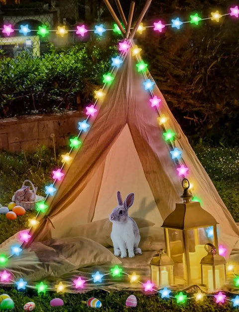 Lit 32 8Ft RGB Fairy Lights With 66 Acrylic Star LEDs illuminate a tent setup with bunny, lanterns, and festive decor outdoors.
