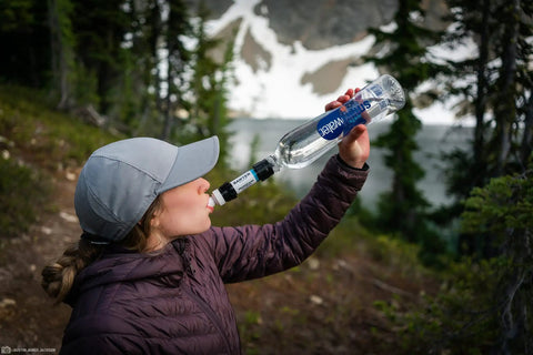 Person using Compact Palm-Sized Water Filtration System With Dual Threaded Mini Plus And Faucet Adapter in outdoor setting.
