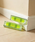 2 Pack Magnetic Mini Bubble Level Tool 2 Inch, Small Pocket resting against a wall corner on wood flooring.