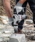 Person using Beast 1200W Electric Rotary Hammer SDS Plus Drill With Swivel Handle on concrete block outdoors