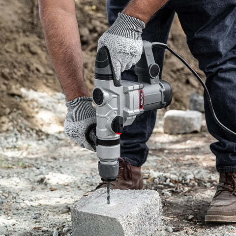 Person using Beast 1200W Electric Rotary Hammer SDS Plus Drill With Swivel Handle on concrete block outdoors