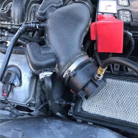 Installed DPTOOL turbo leakage tester kit connected to car intake hose in engine bay; black plastic fittings with brass port.