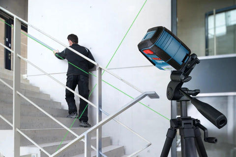 Green Beam Self-Leveling Cross-Line Laser Kit With 40 Ft Range on tripod, projecting lines for alignment on stairs.