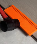 Pro Grade Three Edge Tapping Block for Vinyl Flooring and Laminate Installations next to mallet and flooring plank