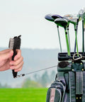 Hand holding retractable club brush with golf bag, part of Two Black Microfiber Waffle Golf Towels With Retractable Club Brush Pro Grade Clean Up For Dirt Mud Sand Grass Must Have Golf Gear And Cleaning Kit For Clubs.