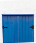 Front view of blue wooden outdoor shed door with black heavy-duty hinges and vertical planks