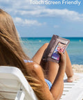 Woman using Waterproof Fanny Pack And Dry Bag Set for phone on beach in lounge chair, showing touch screen function.