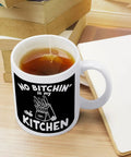 No Bitchin' In My Kitchen 11 Oz Ceramic White Mug on desk with tea, surrounded by books and notebook, Comfortable Handle