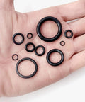 Hand holding multiple rubber O-rings from 1010 Piece Rubber O Ring Kit With 22 Sizes Universal O Ring Set For Automotive Faucets Pressure Washers Plumbing Sealing Repair Oil Gas Air Applications Heat Resistant