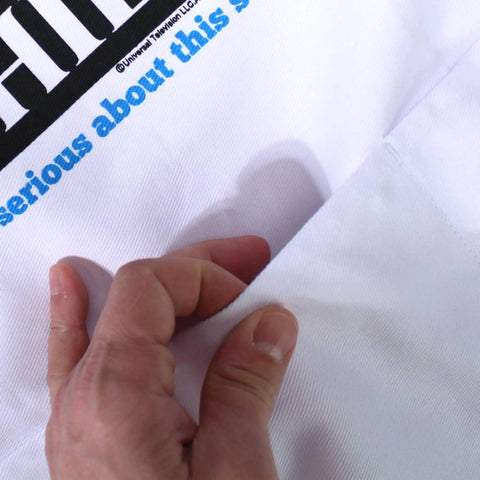 Close-up of hand touching pocket on "The Office Inspired Kevin's Famous Chili Cook-Off Fan Favorite Apron With Pockets And Adjustable Neck Strap 100 Percent White Cotton For Kitchen BBQ Grilling And Crafting"