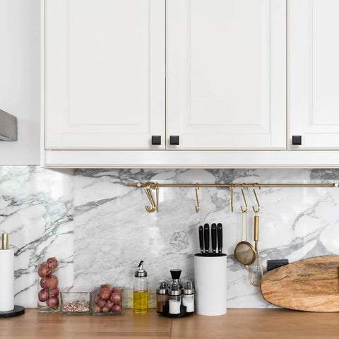 Kitchen with marble backsplash, white cabinets, matte black square cabinet knobs, 1 inch, modern farmhouse style pulls visible.