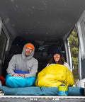 Two people camping in van with gear, including the Two Person Camping Mess Kit With Insulated Mugs in blue and green.