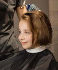 Front view of NICEMOVIC black barber cape with white neck collar and blue neck duster brush on head