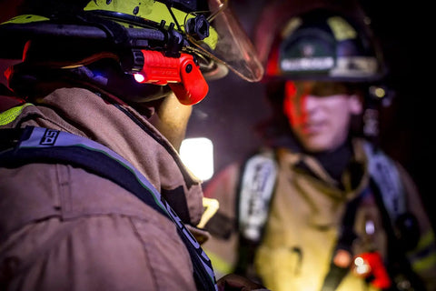 Firefighter using LED Helmet Light With 180 Degree Articulating Head And Dual Beam Output in dark environment, orange light visible