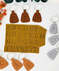 Dope 26 Piece Alphabet Polymer Clay Cutters Set Uppercase Letters shown on clay with keychains and flowers