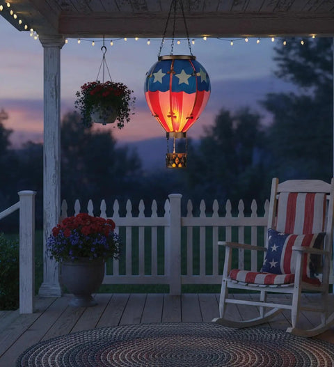 Hot Air Balloon Solar Lantern Outdoor Hanging LED Light for Garden Patio Pathway, metal and glass with flickering flame effect at sunset.