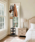 Dope Freestanding Coat Rack With 12 Hooks And Umbrella Holder in bedroom next to window and nightstand.