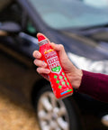 Hand holding StaySafe All In One Portable Fire Extinguisher that handles ten types of fires near a car, eco-friendly formula