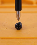 Grab These Happyyami M4x14mm Black Pan Head Self Tapping Screws With Cross Recess And Flat Point, Perfect For Wood Cabinet Hardware And Small Machine Assemblies, 200 Piece Set. Close-up of black screw and screwdriver.