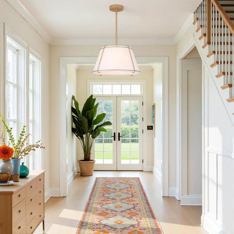 16" White and Gold Drum Pendant Light with Metal Lantern Fabric Shade hanging in a bright hallway with large windows.