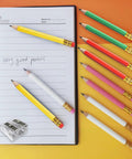 Premium 25-Pack Hexagonal Wooden Golf Pencils with Built-In Erasers and Graphite 2B Lead in assorted colors next to a notebook.