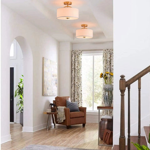13 Inch Mid Century Modern Flush Mount Ceiling Light With Cream White Fabric Shade And Antique Brass Finish 3 Light Drum Fixture For Bedroom Dining Room Foyer And Kitchen shown installed in a living room.
