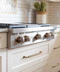 Kitchen with Antique Brass Cabinet Pulls Set, Solid Zinc Alloy Drawer Handles on white cabinets near a stainless steel stove.