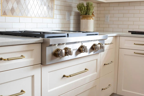 Kitchen with Antique Brass Cabinet Pulls Set, Solid Zinc Alloy Drawer Handles on white cabinets near a stainless steel stove.
