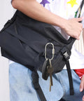 Solid Brass Carabiner Keychain Clip With Screw Lock Built To Last Rugged Key Organizer on a black backpack strap.