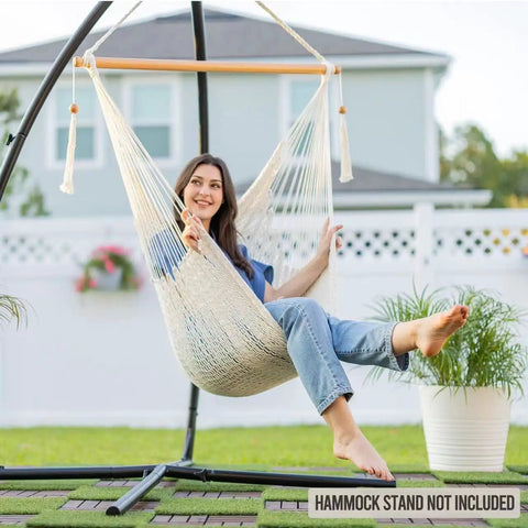 Woman relaxing in Caribbean Style Hammock Chair With Spreader Bar, XL Rope Hanging Chair, Natural White, in garden setting.