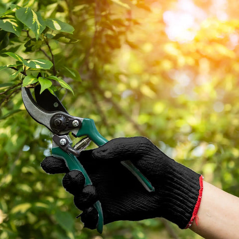 Hand holding pruning shears while wearing Tough As Nails Nitrile Coated Work Gloves Bulk Pack Of 72 Pairs For Mechanics And Yard Jobs.