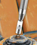 Close-up of a knurled metal grease joint rejuvenator tool attaching to a rusted bearing joint.