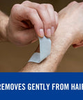 White Nexcare strong tape being peeled from forearm; fabric adhesive tape for sensitive skin.