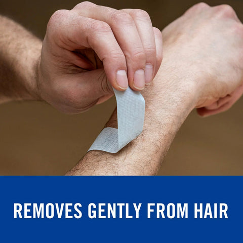 White Nexcare strong tape being peeled from forearm; fabric adhesive tape for sensitive skin.