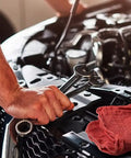 Mechanic using tools with Red Cotton Shop Towels Pack Of 150 14 By 14 Inch Absorbent Cleaning Rags on car hood for garage use.