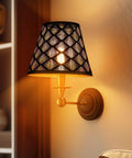 Wall-mounted lamp with intricate patterned shade casting warm light in a living room.