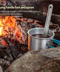 Ultra Lightweight Titanium Long Handle Spork And Spoon Set For Outdoor Camping And Backpacking in a cup near campfire