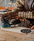Man using orbital sander on wood with 100 Pcs 5 Inch Sanding Discs Hook And Loop With 8 Holes Wet Dry Sandpaper Assortment