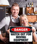 Two people holding a Watch Out For Moving Equipment Sign 8x12 Inch Aluminum Metal Safety Sign in a bakery setting.