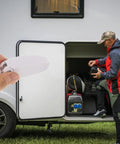 Hand holding Must-Have White Stainless Steel And Abs Baggage Door Catch Clip For Rv Trailer Camper near open RV storage.