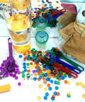 Magnetic Wand And Bingo Chips Set For Kids, colorful bingo chips around glasses, green wand, and bingo card on table.